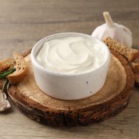 Garlic sauce, ingredients and snack on wooden background